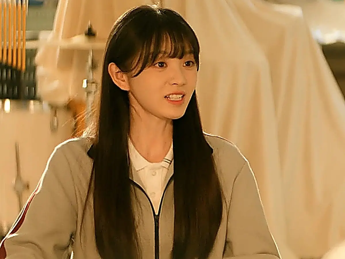 Lin Zhixia discussing festival plans in a sporty zipped track jacket layered over a collared shirt
