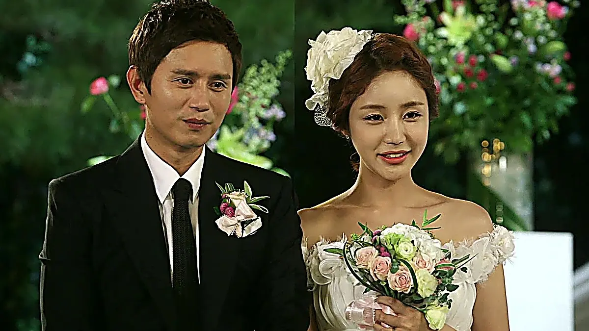 Im Me-ah-ri wearing an off-the-shoulder ruffled bridal mini dress with an oversized white flower hair accessory alongside Choi Yoon in a black notch lapel tuxedo