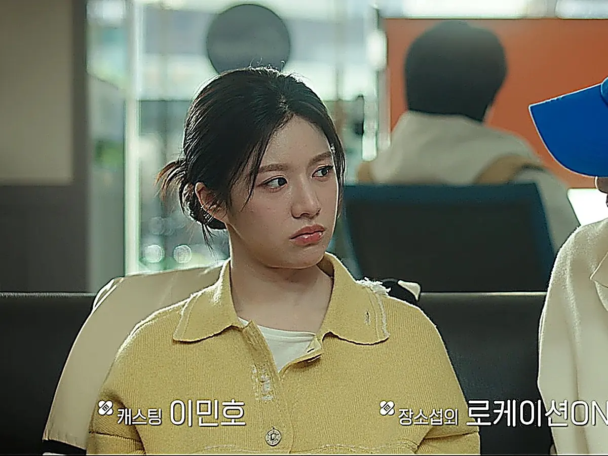 A woman with dark hair tied back wearing a light yellow knit polo collar shirt