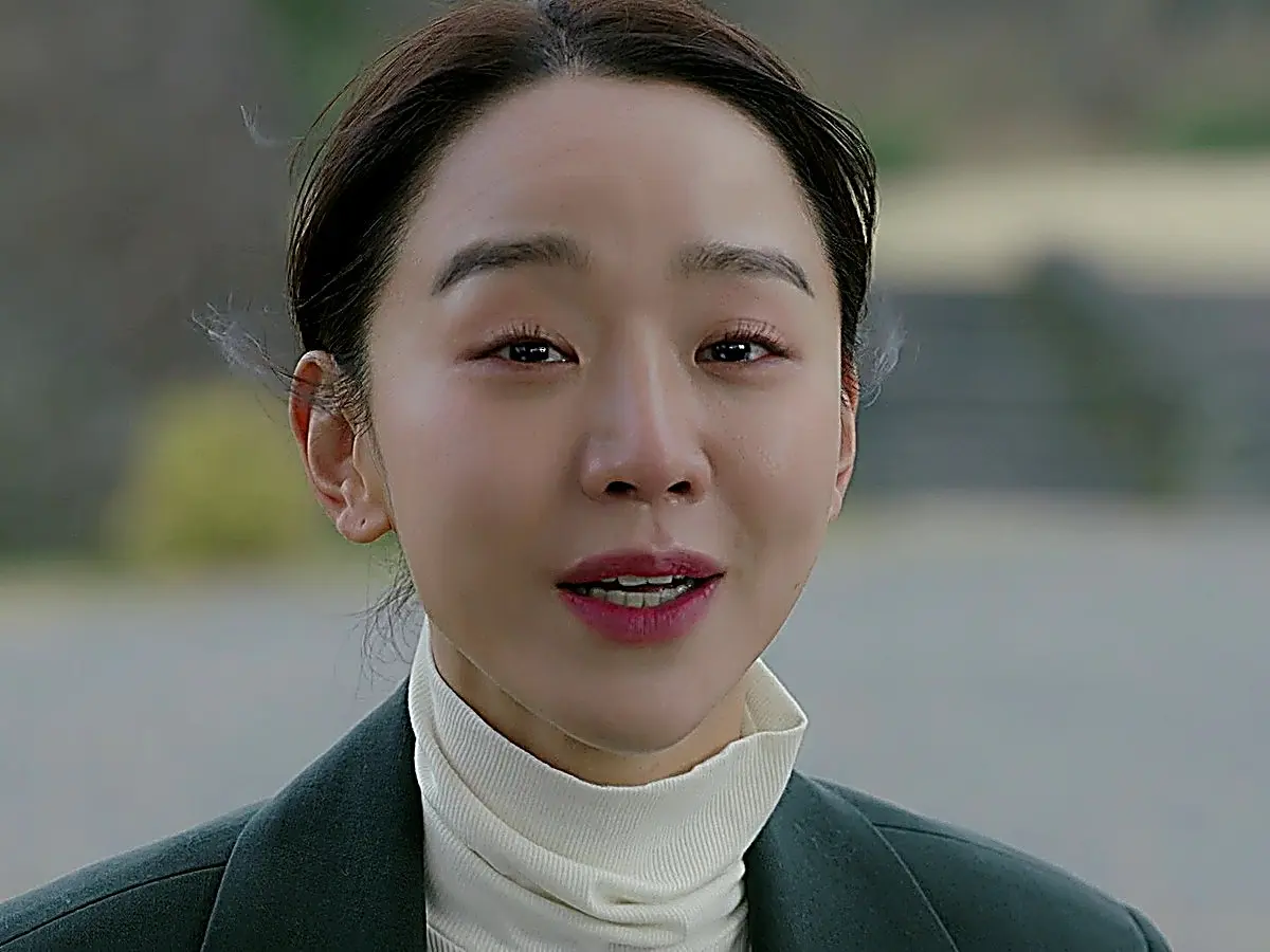 Cho Sam-dal speaking in a dark tailored blazer and white turtleneck