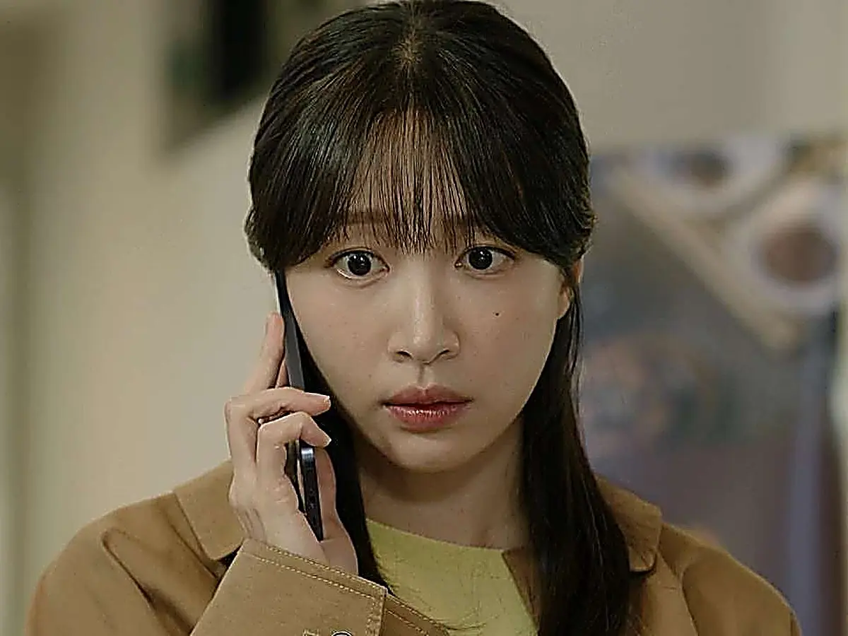 Han Gyu-rim holding a phone to her ear while wearing a tan button-down shirt over a crewneck shirt
