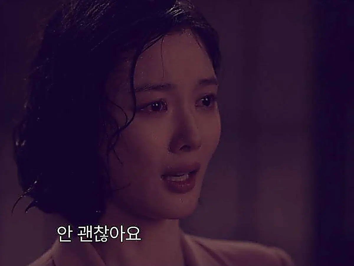 A woman with wet hair and tears on her face looking forward with parted lips in the rain