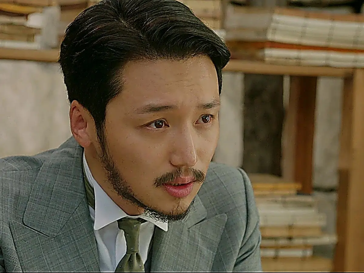 Kim Hui-seong wearing a grey tailored three-piece suit with peaked lapels