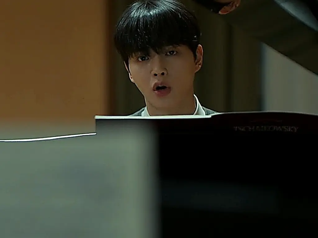 Kang Bi-o sitting at the grand piano in the rehearsal studio discussing concerto dynamics