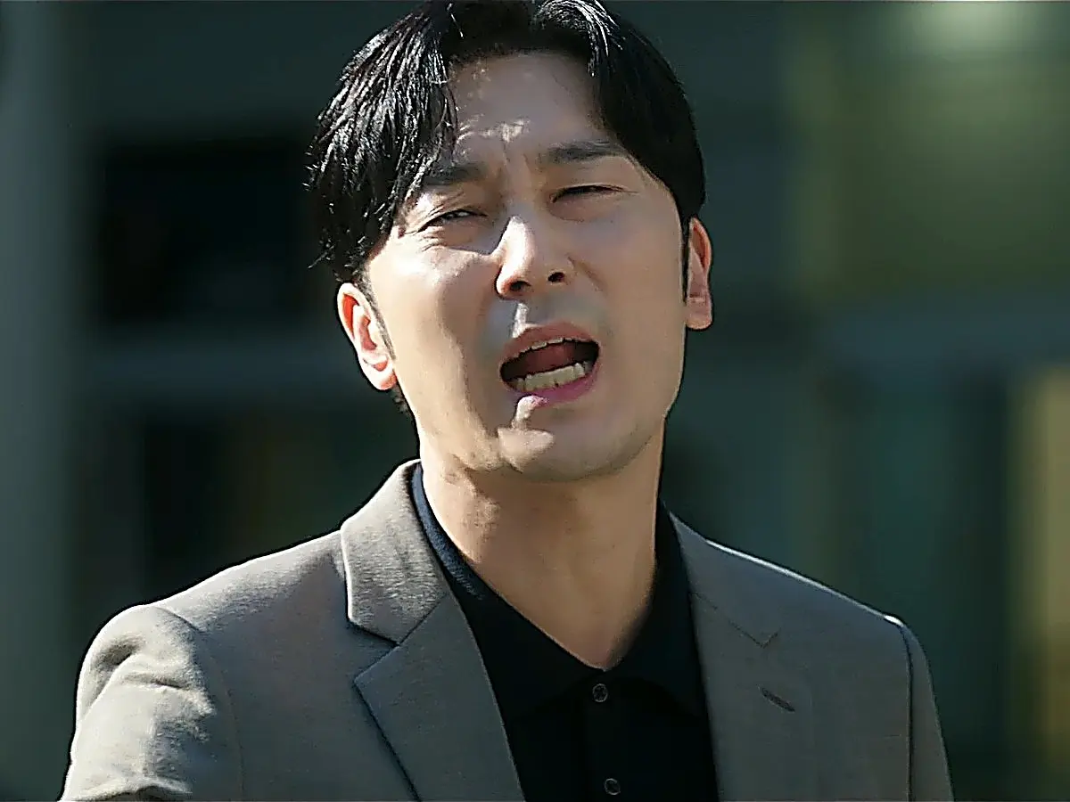 Yang Jun-ho wearing a beige sport coat over an open-collar black knit polo shirt