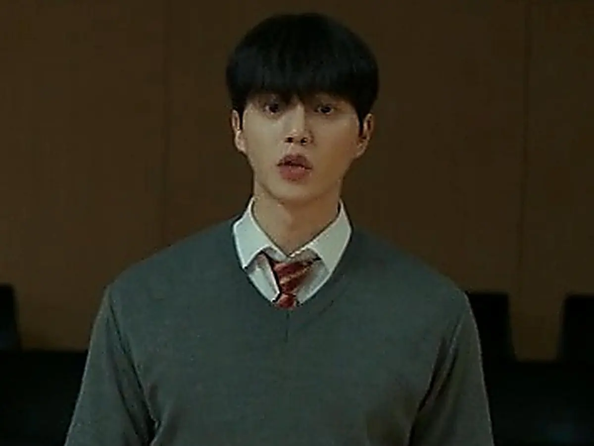 Kang Bi-o wearing a grey v-neck knit sweater and tie in a practice hall