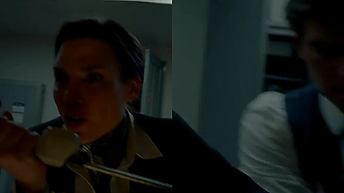 Flight attendant in structured dark tailored vest and white collared shirt holding cabin interphone