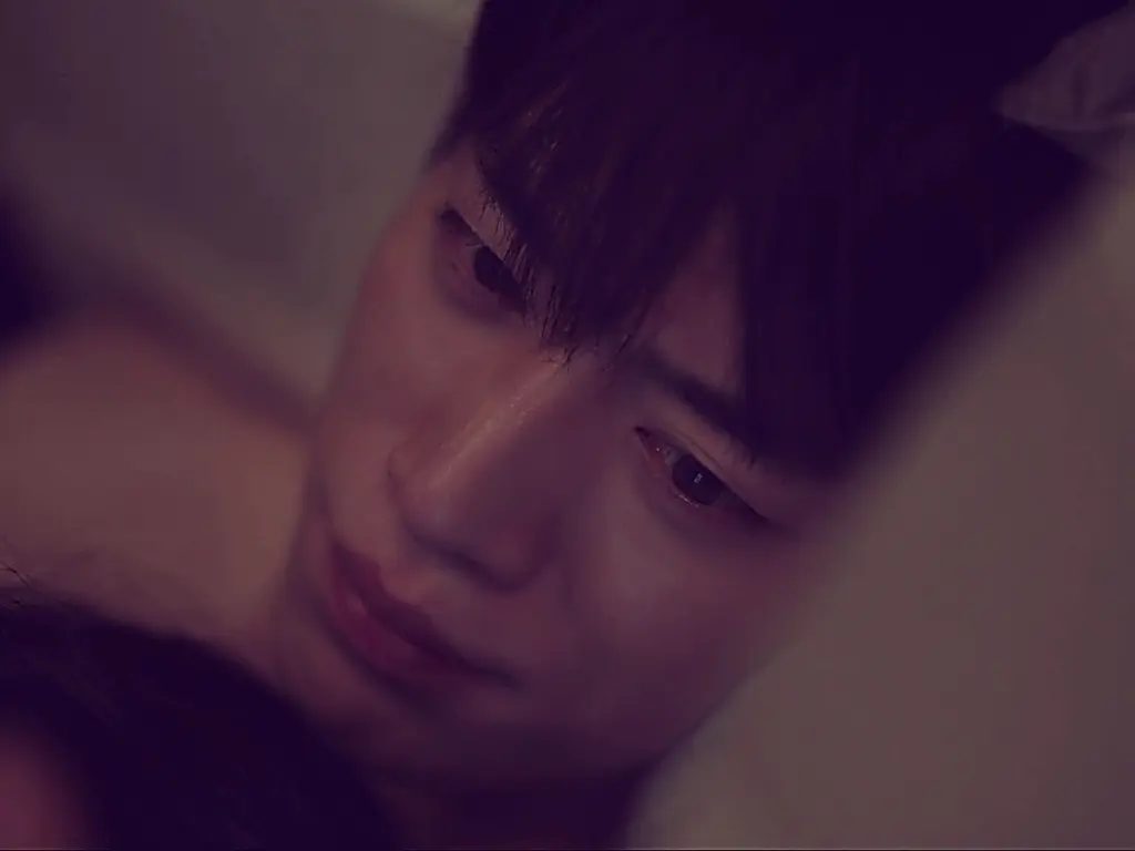Close-up angled shot of a man resting his head under dim purple lighting