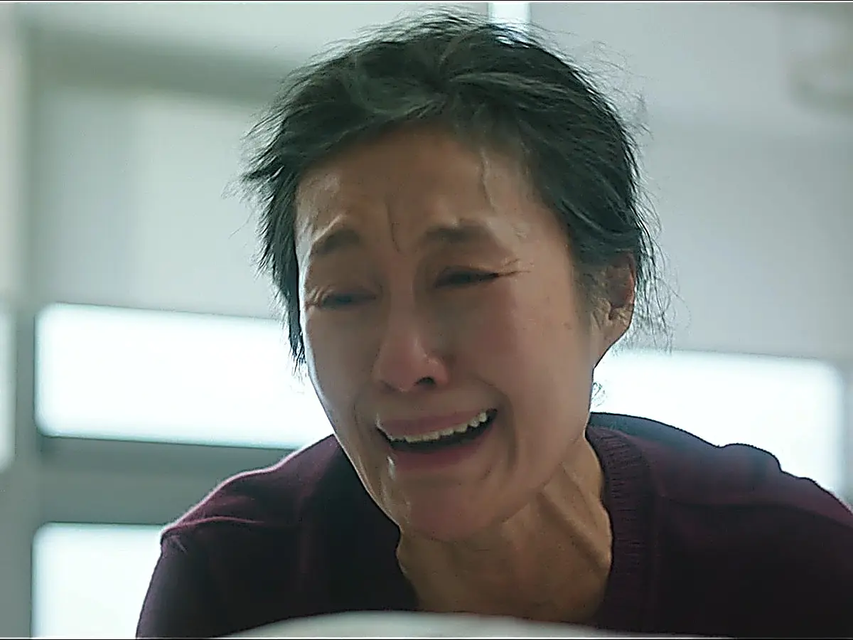 A middle-aged woman in a dark sweater crying openly