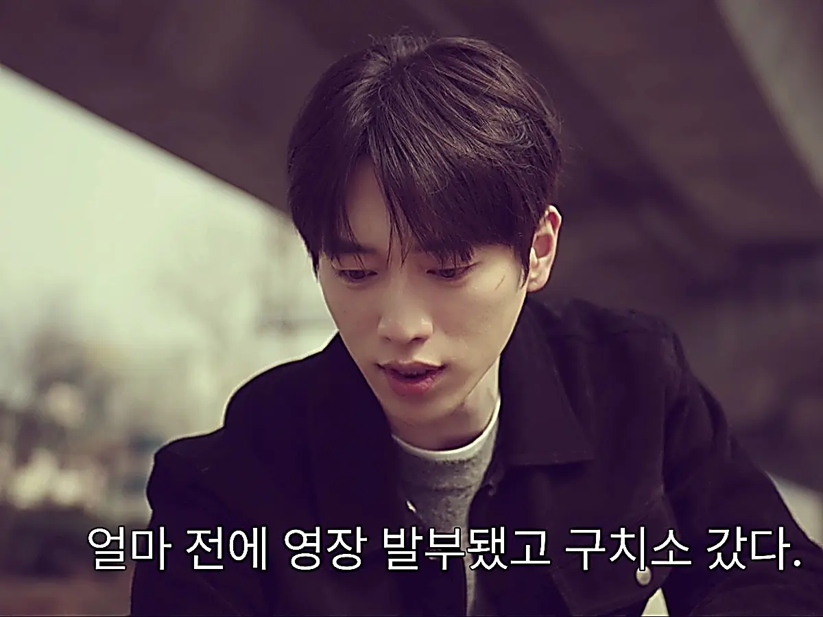 Namgung Ho wearing a dark zip blouson over a crewneck grey knit sweater
