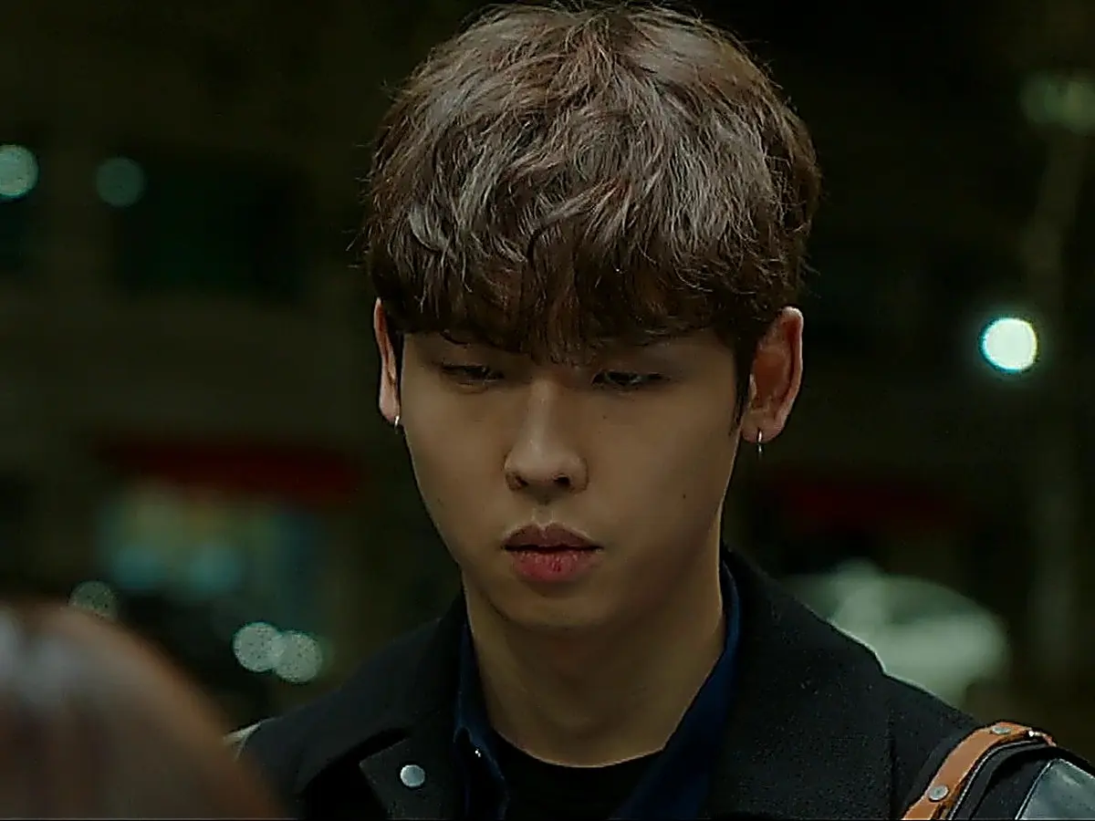 Close-up of a young man looking down outdoors at night wearing a dark jacket