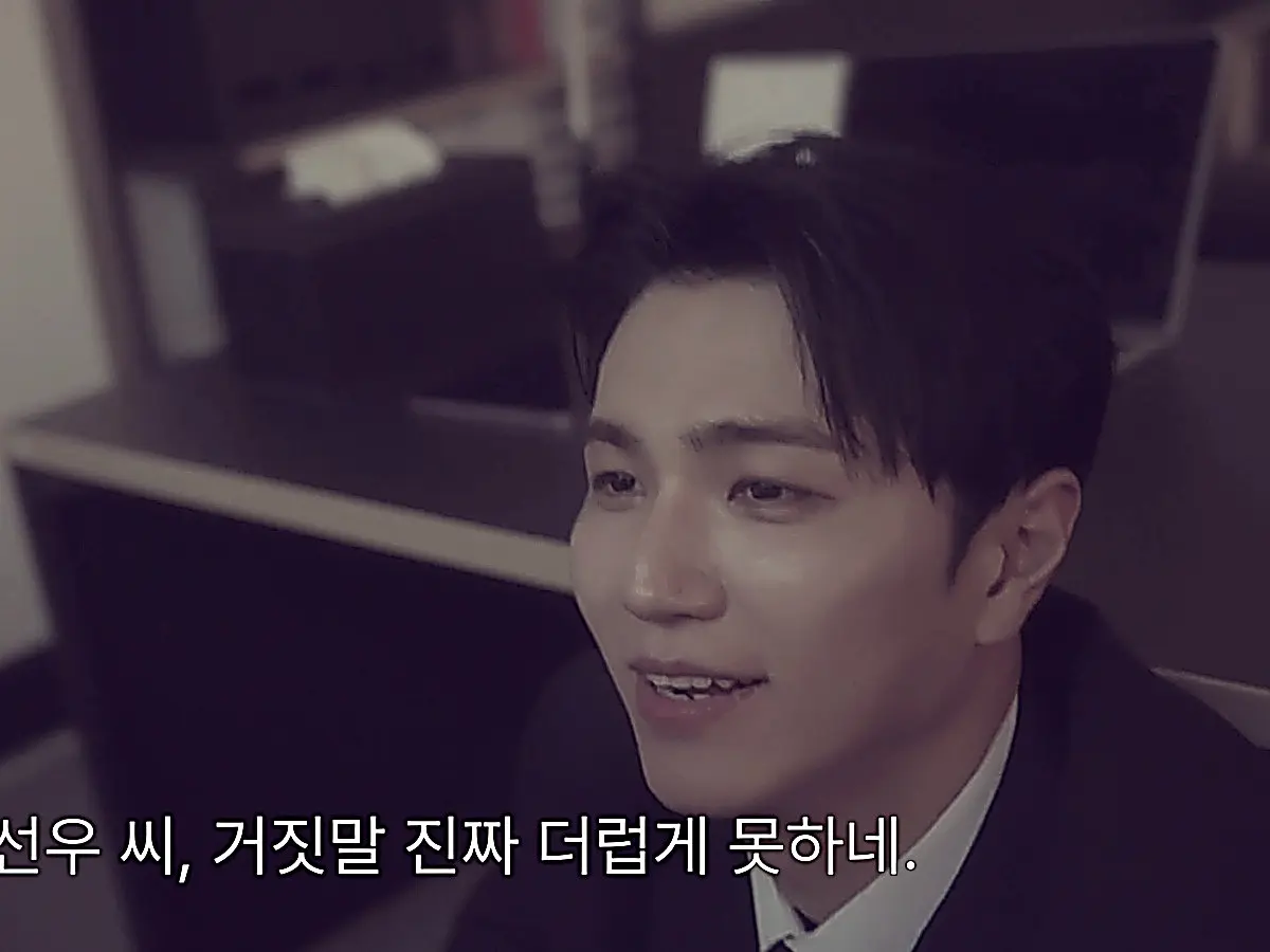 Kang Do-jin looking up with an amused expression from beneath the desk