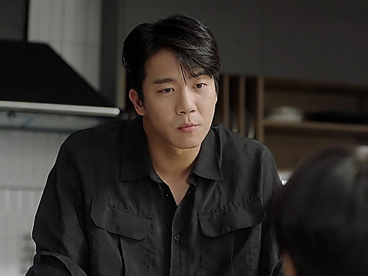 Mu-jin wearing a dark collared long-sleeve button-down shirt with front chest pockets