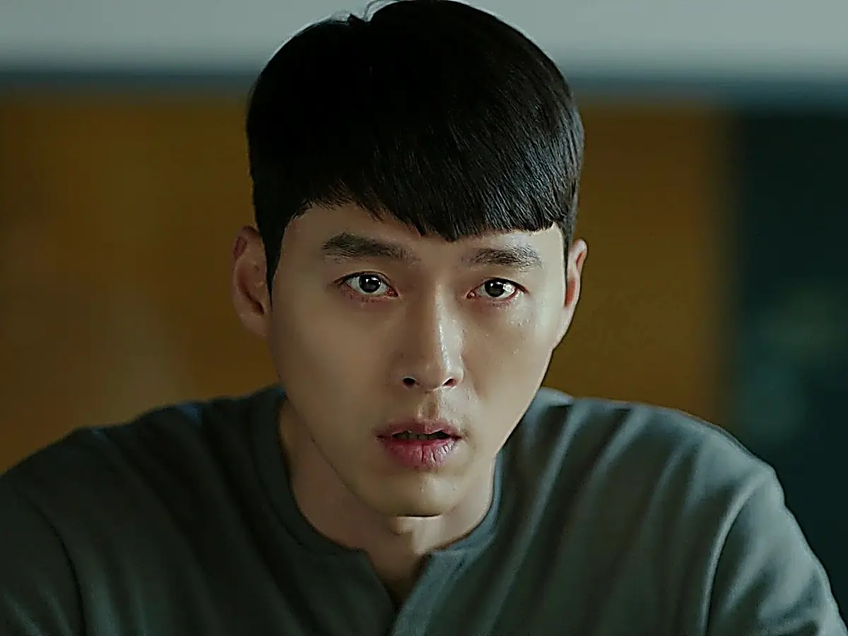 A man in a dark grey crewneck top staring forward with a firm and strained expression.