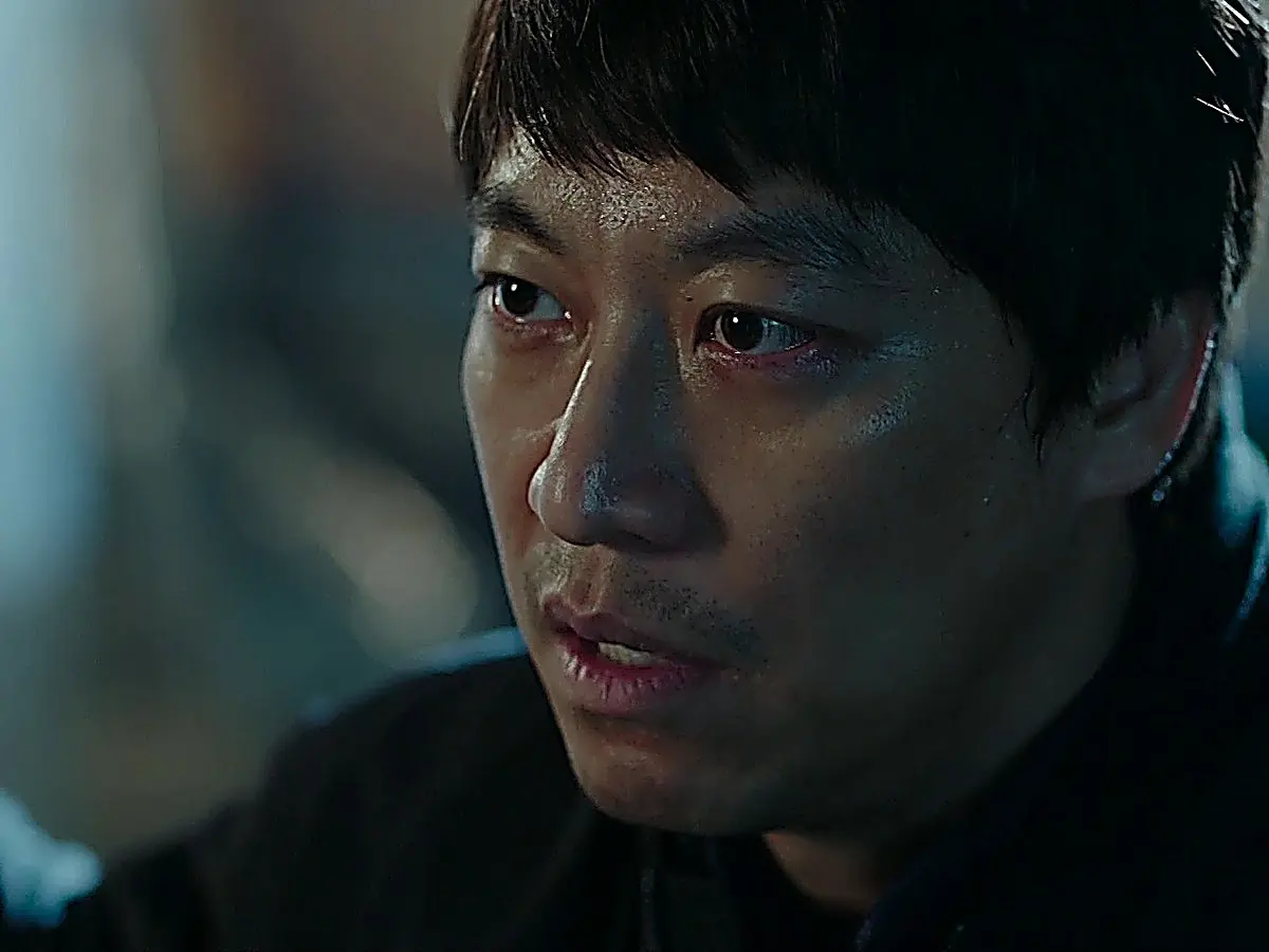 Close-up of a man with glistening skin and a grazed face speaking fiercely