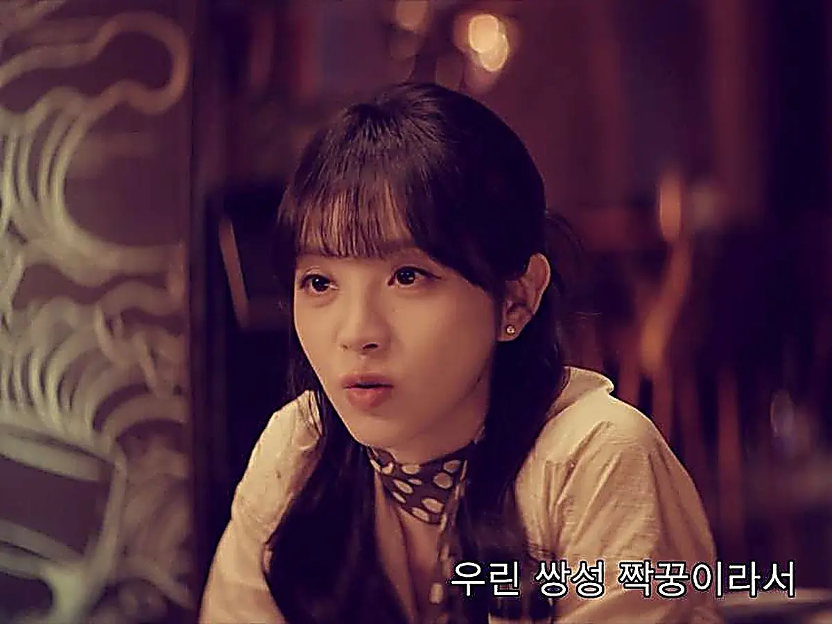 Lin Zhixia seated at a table wearing a cream top accented with a patterned neck scarf