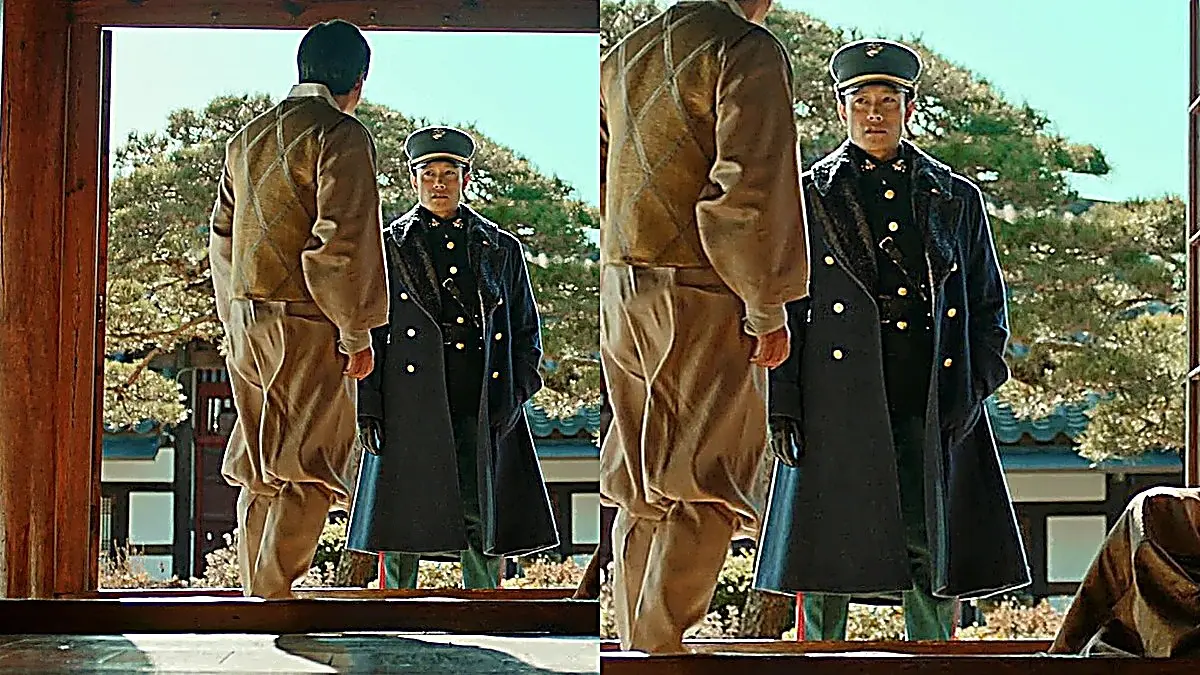 Eugene Choi standing in a courtyard wearing a dark double-breasted military overcoat with brass buttons