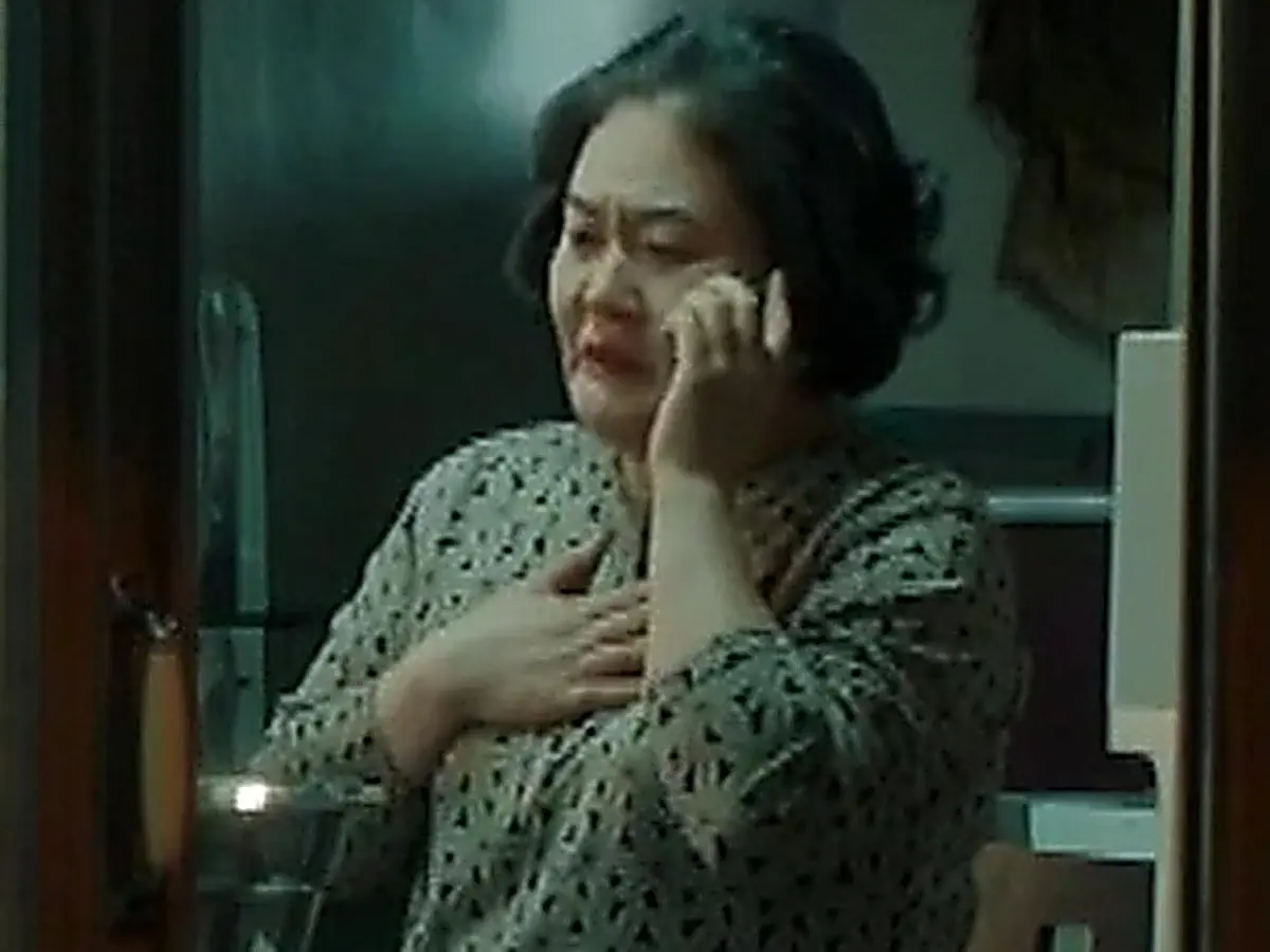 A woman holding a phone to her ear with one hand placed over her chest