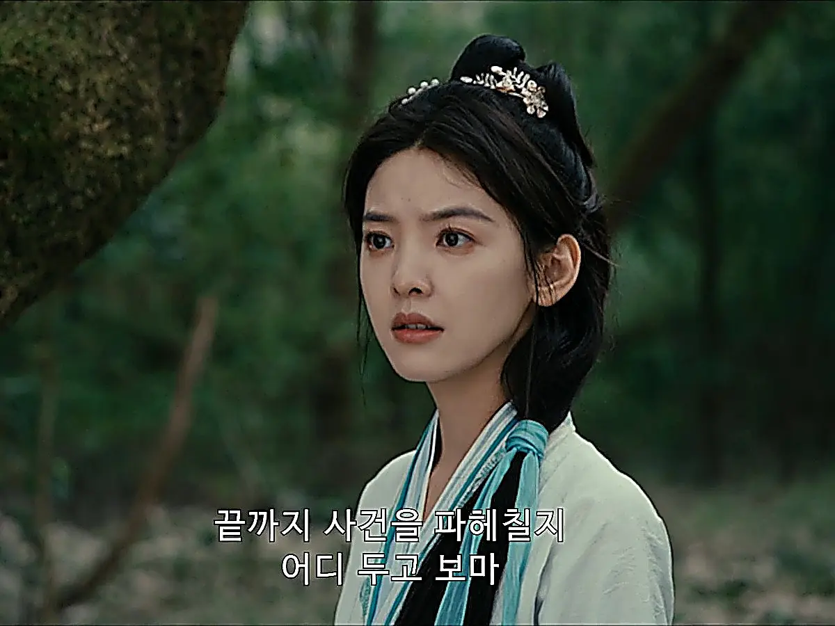 A young woman wearing a white robe with blue trim and floral hairpins looking forward with a tense expression