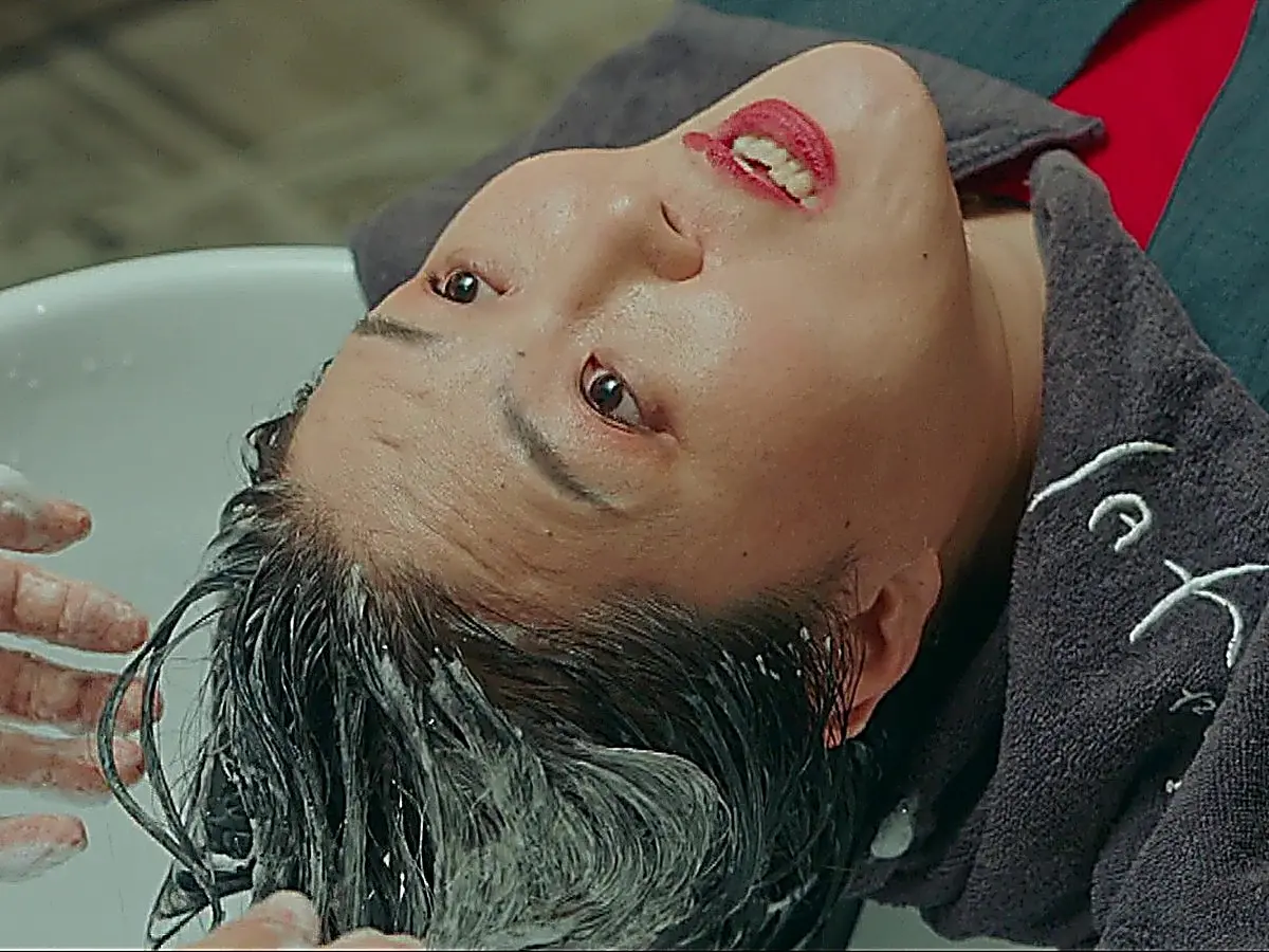 A woman lying back on a shampoo chair with lathered hair