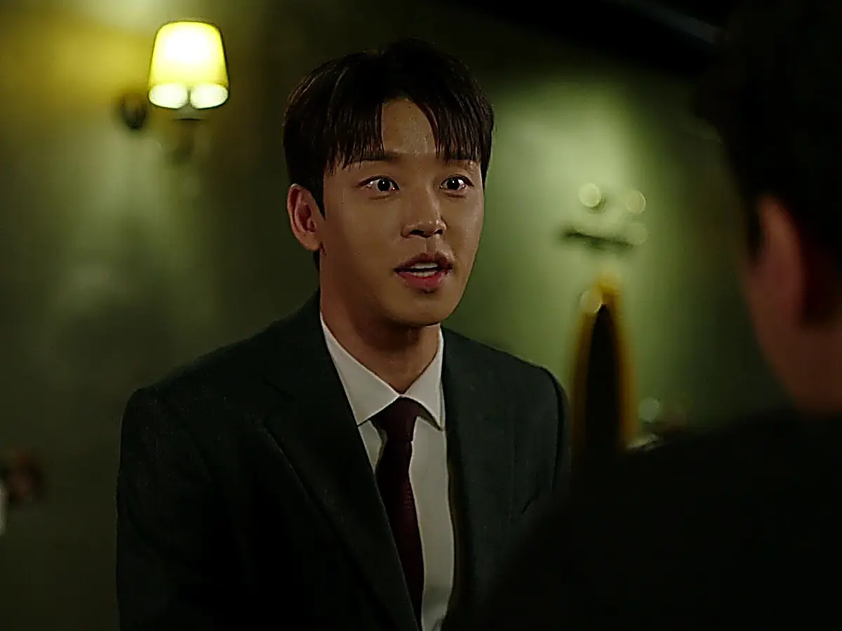 Cha Seok-jin wearing a dark tailored suit jacket over a white dress shirt and burgundy tie at an alumni gathering