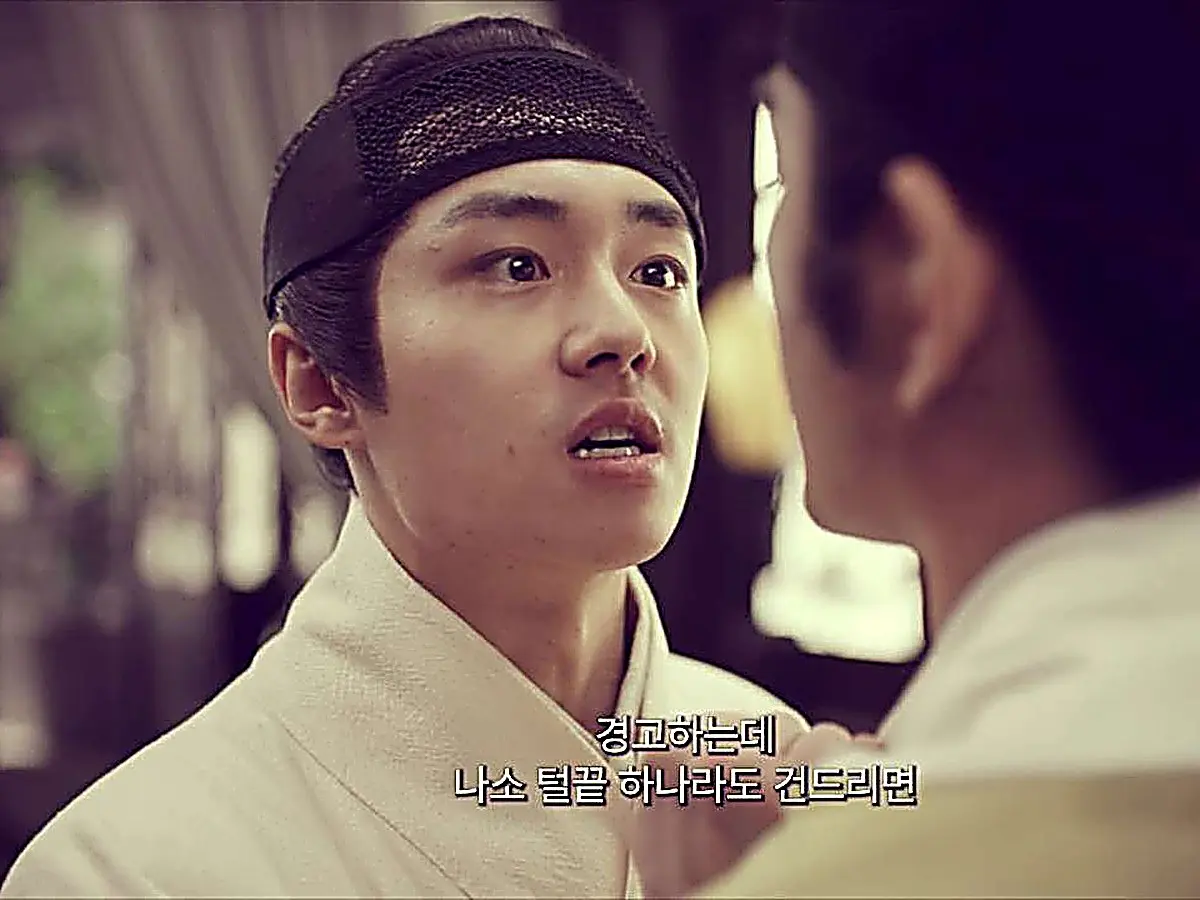 A young man in a white robe confronting another person with wide eyes