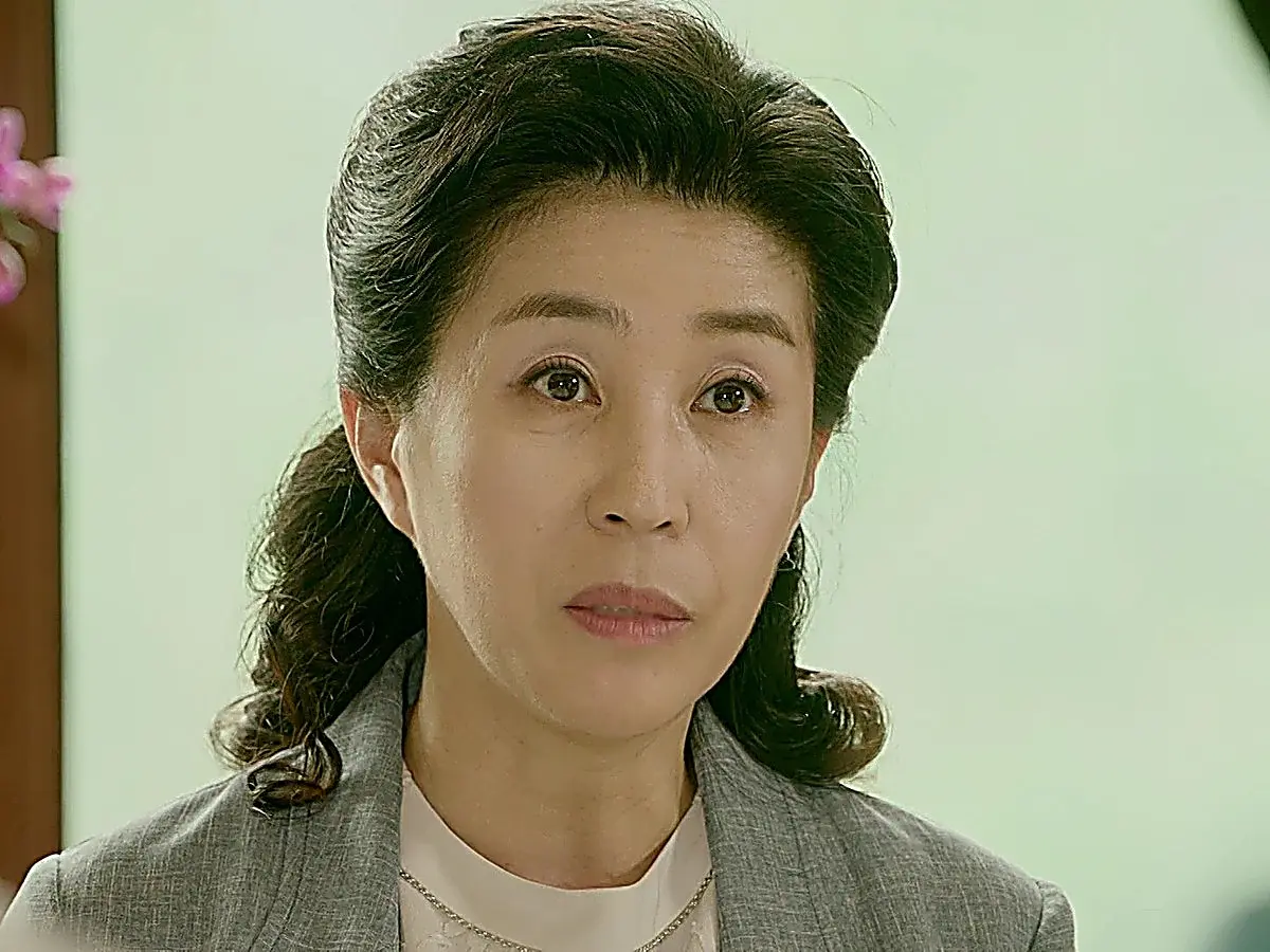 Hwang Deok-yi wearing a tailored grey suit jacket with a soft white inner layer