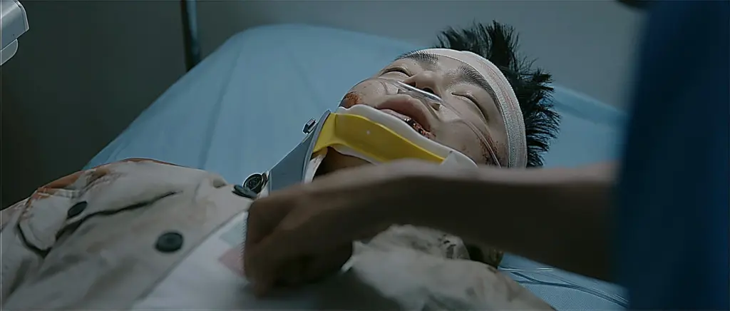 An injured man with a white head bandage and yellow neck brace lying on a stretcher.