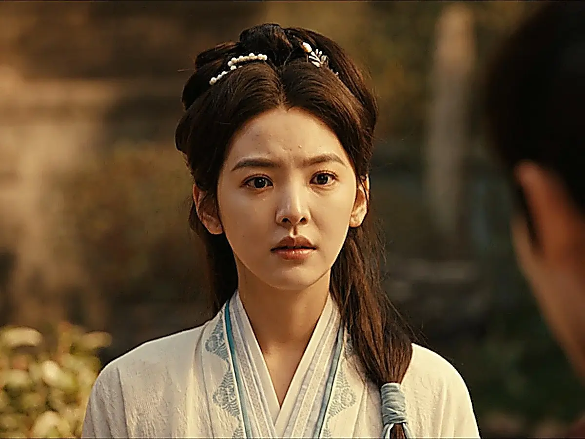 Guo Yinglong dressed in an off-white crossover robe with subtle blue patterned trim, wearing a pearl floral hair clip in her high updo