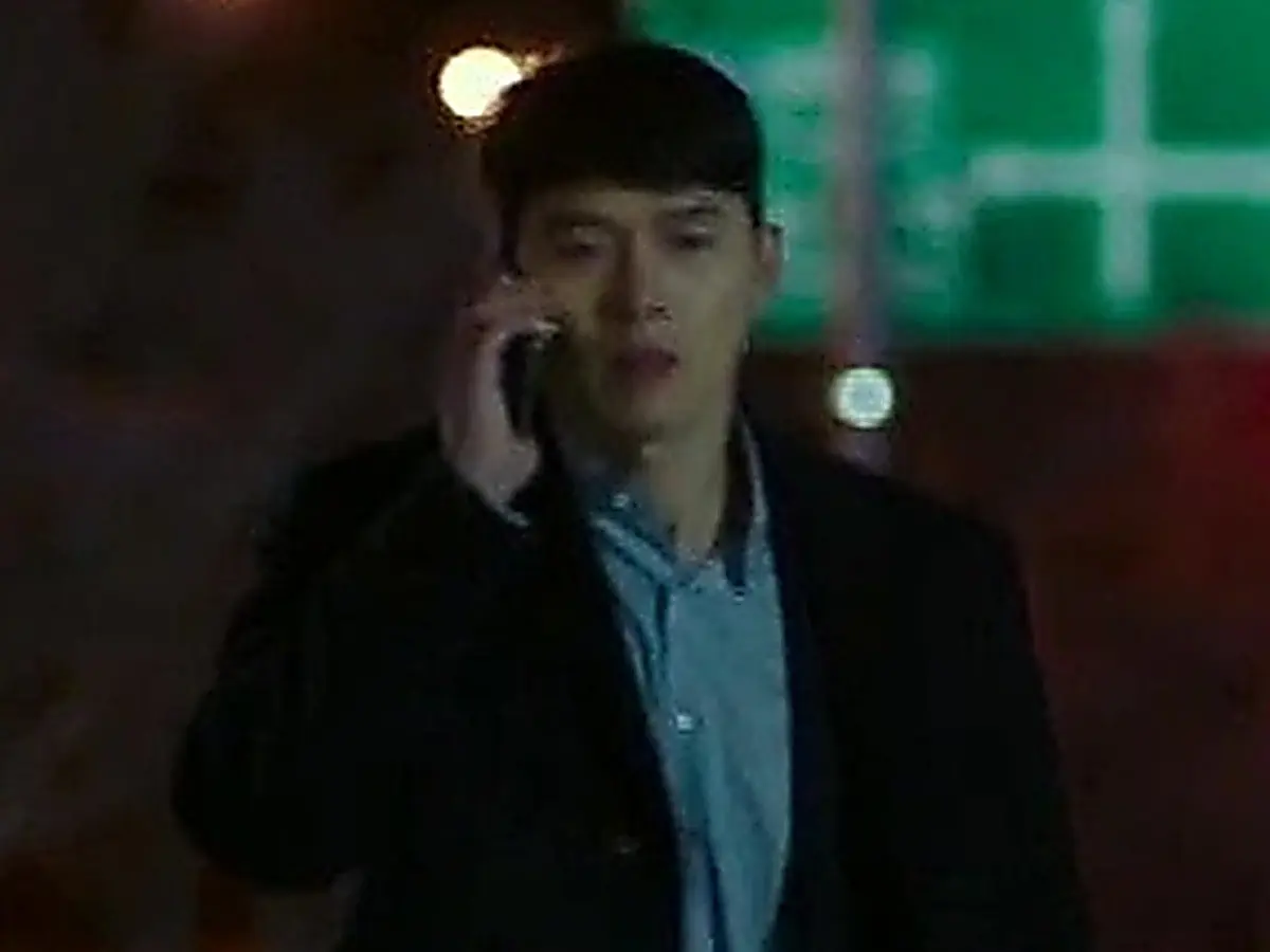 Ri Jeong-hyeok wears a dark coat layered over a light blue collared shirt while rushing along a night street
