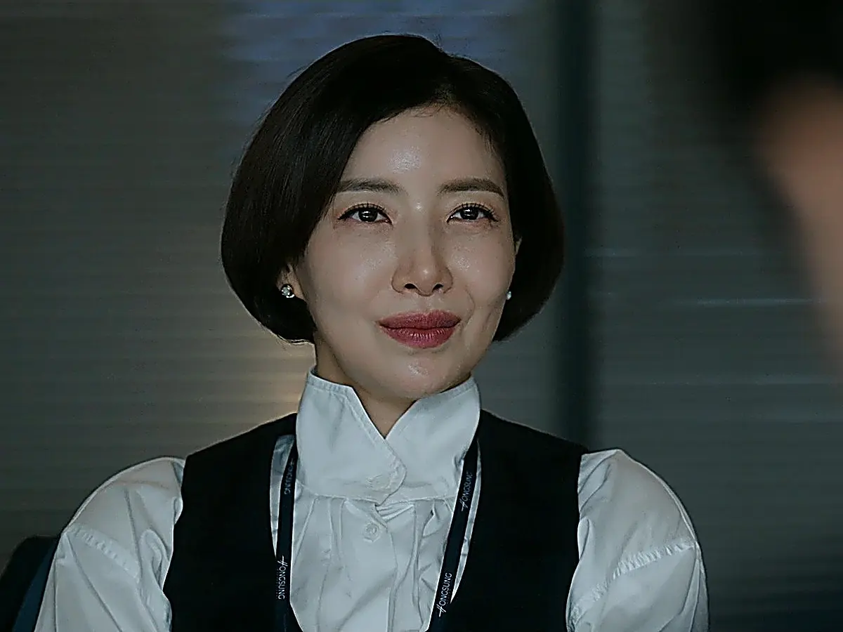 Martina in an office setting wearing a dark tailored vest over a high-collar white blouse